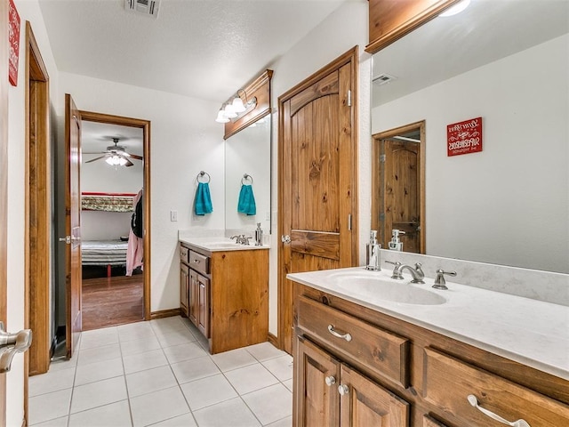 ensuite bathroom featuring two vanities, visible vents, connected bathroom, a sink, and tile patterned flooring