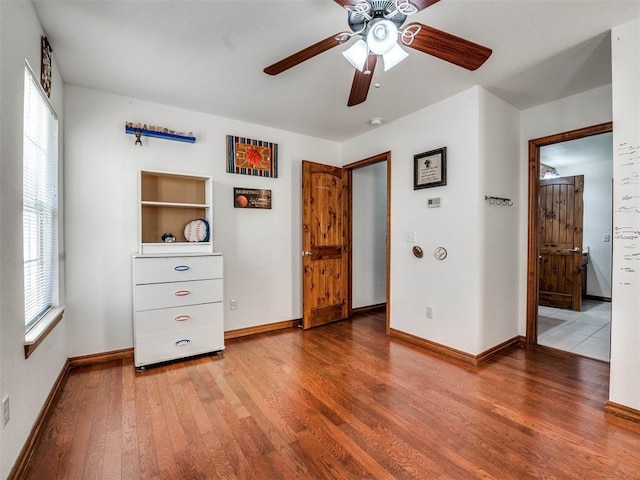 unfurnished bedroom with ceiling fan, baseboards, and wood finished floors