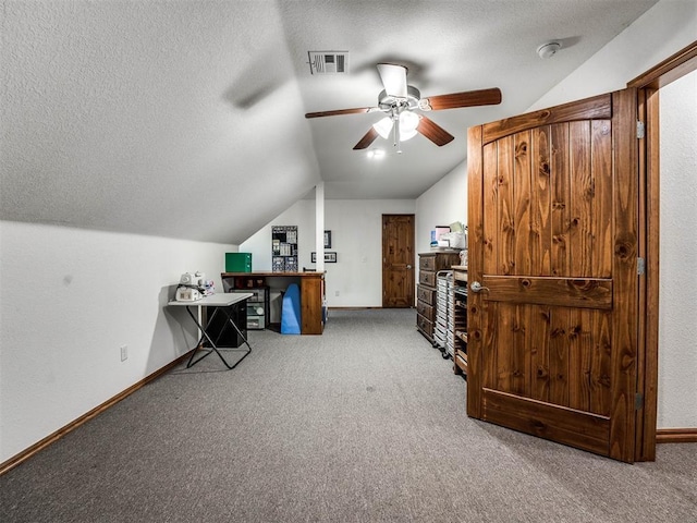 office space featuring baseboards, visible vents, carpet, vaulted ceiling, and a textured ceiling