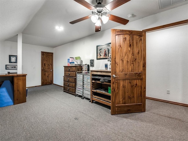 carpeted home office with baseboards, visible vents, vaulted ceiling, and a ceiling fan