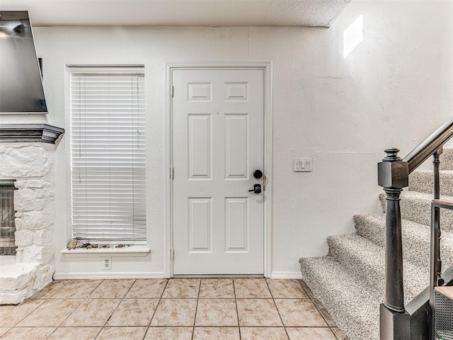 foyer entrance with stairway, baseboards, and light tile patterned floors