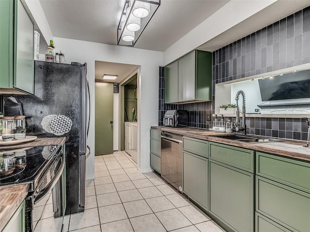 kitchen with butcher block counters, green cabinets, stainless steel dishwasher, black range with electric cooktop, and independent washer and dryer