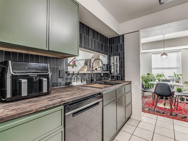 kitchen featuring green cabinets, a sink, stainless steel dishwasher, and light tile patterned flooring