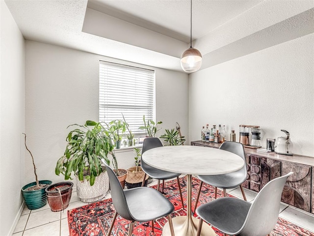 dining room featuring a textured ceiling, baseboards, and light tile patterned floors