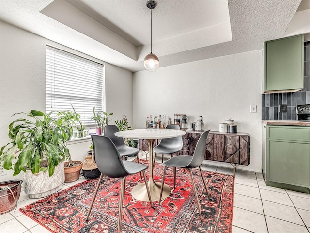 dining space with a raised ceiling, a textured ceiling, and light tile patterned flooring