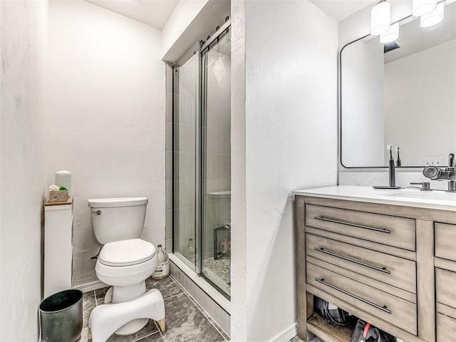 bathroom with toilet, a stall shower, and vanity