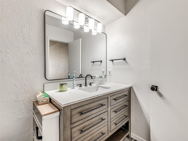 bathroom with a textured wall and vanity