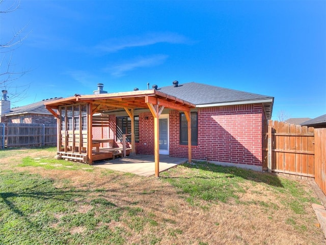 back of property with a lawn, a fenced backyard, roof with shingles, a patio area, and brick siding