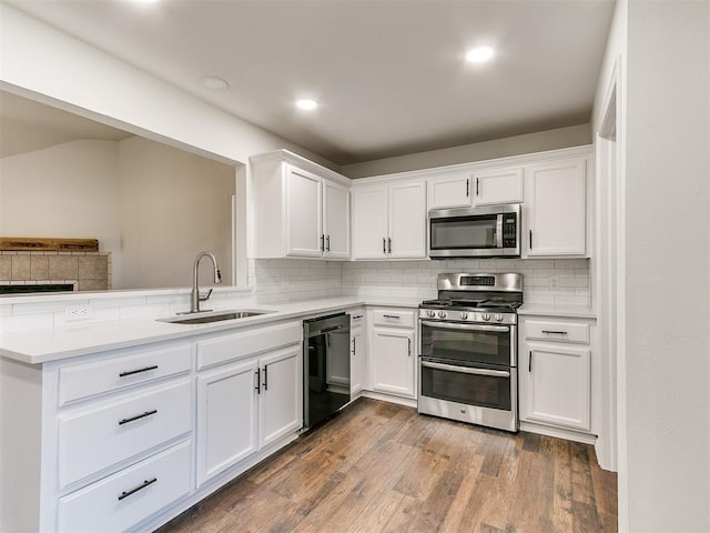 kitchen featuring stainless steel appliances, a sink, white cabinetry, light countertops, and dark wood-style floors