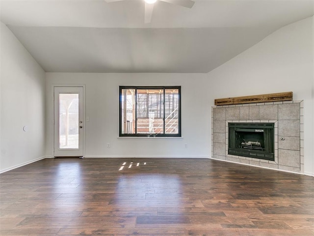 unfurnished living room featuring wood finished floors, a ceiling fan, baseboards, vaulted ceiling, and a tiled fireplace