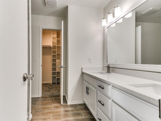 full bath featuring baseboards, visible vents, a walk in closet, wood finish floors, and a sink