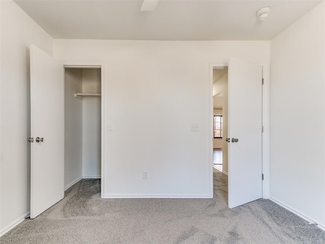 unfurnished bedroom with a spacious closet, a closet, carpet flooring, and baseboards