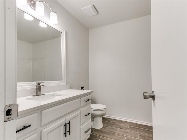 bathroom featuring wood finish floors, baseboards, vanity, and toilet