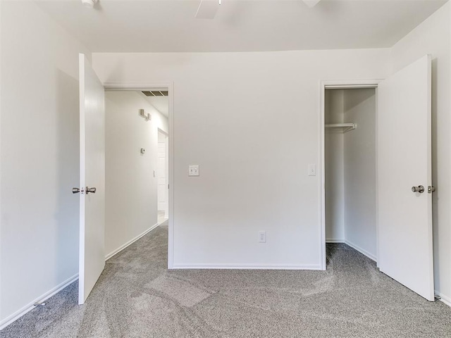 unfurnished bedroom featuring a closet, carpet, a walk in closet, and visible vents