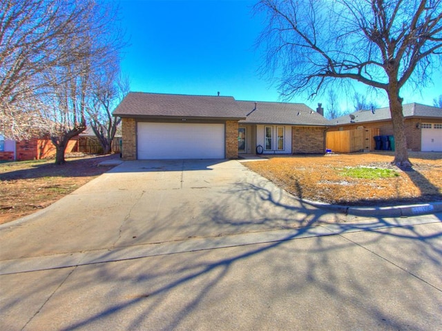 view of front of home featuring fence, driveway, a chimney, a garage, and brick siding