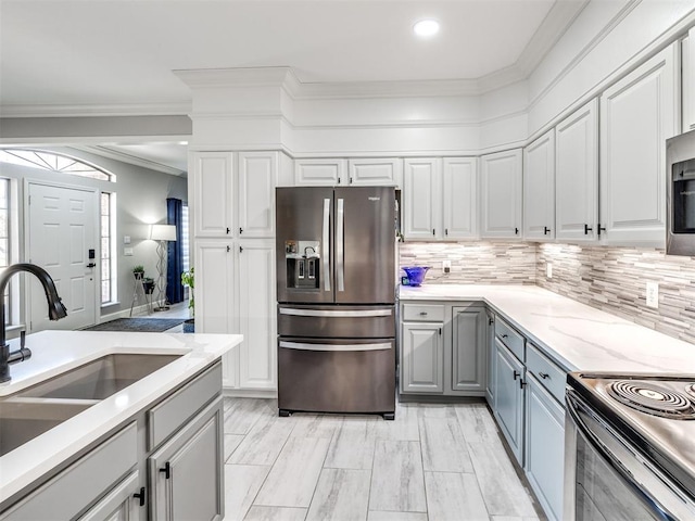 kitchen featuring stainless steel refrigerator with ice dispenser, tasteful backsplash, gray cabinetry, white cabinets, and a sink