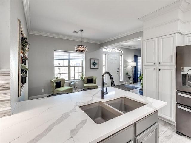 kitchen featuring visible vents, ornamental molding, decorative light fixtures, white cabinetry, and a sink