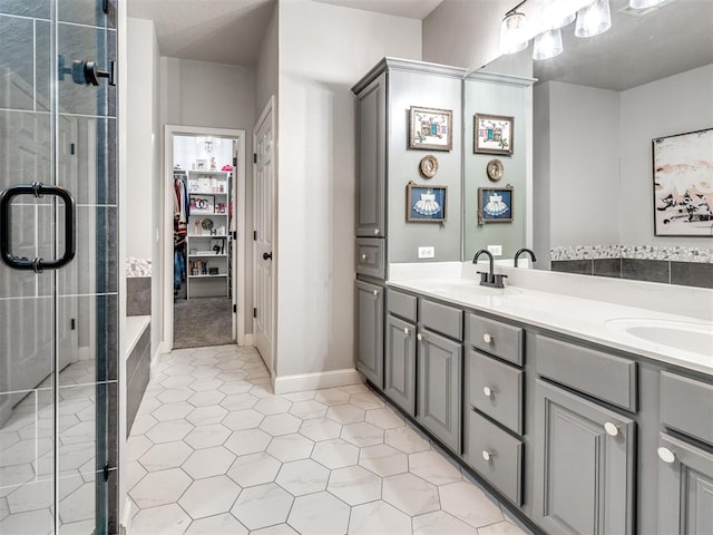 full bath featuring double vanity, a spacious closet, a sink, and tile patterned floors