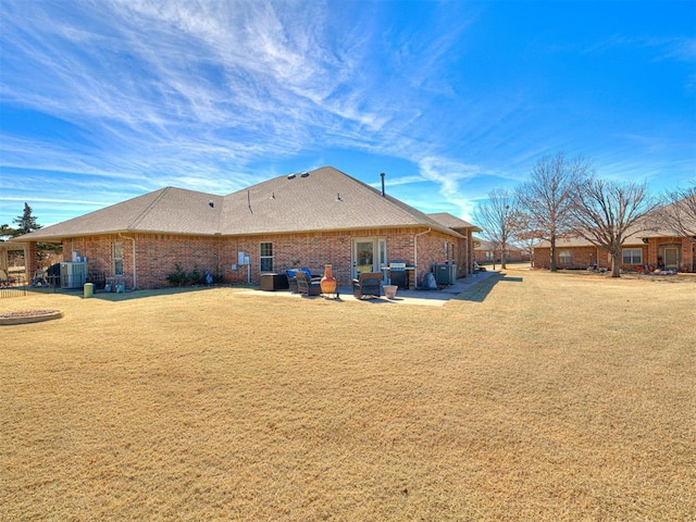 back of property featuring a patio area, a lawn, and brick siding