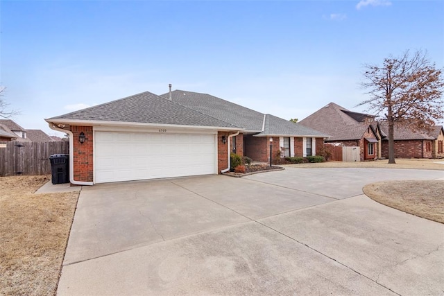 ranch-style house with concrete driveway, brick siding, fence, and roof with shingles