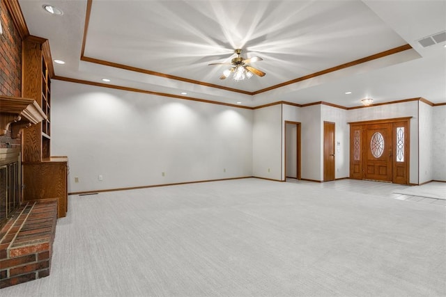 unfurnished living room with a brick fireplace, baseboards, a tray ceiling, and light colored carpet