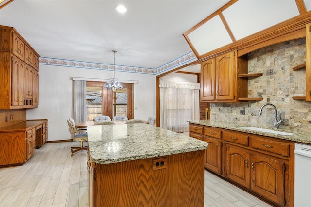 kitchen with tasteful backsplash, a kitchen island, white dishwasher, a chandelier, and a sink