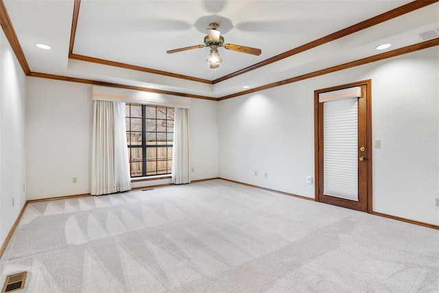 unfurnished room with light colored carpet, baseboards, visible vents, and a tray ceiling