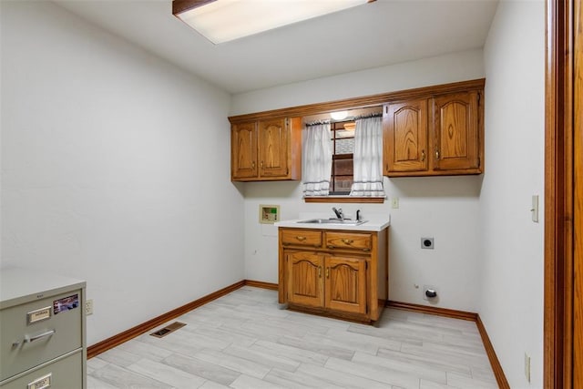 clothes washing area featuring washer hookup, cabinet space, hookup for an electric dryer, a sink, and baseboards