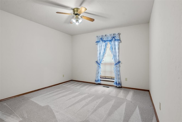 carpeted empty room featuring ceiling fan, visible vents, and baseboards