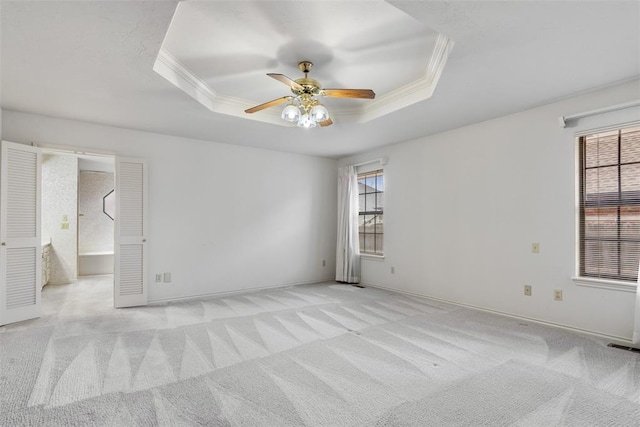 unfurnished room featuring light carpet, ornamental molding, and a raised ceiling