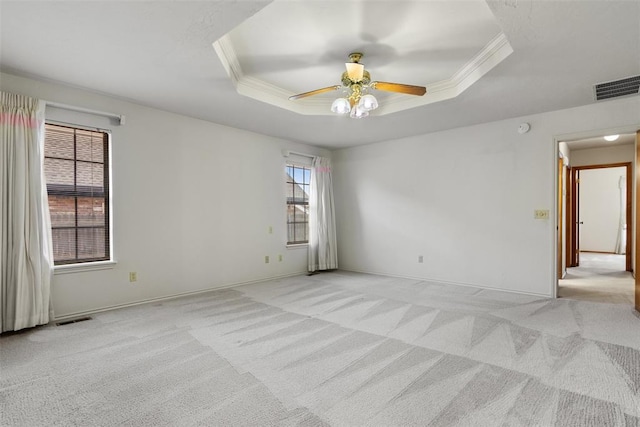 unfurnished room with a tray ceiling, visible vents, and crown molding