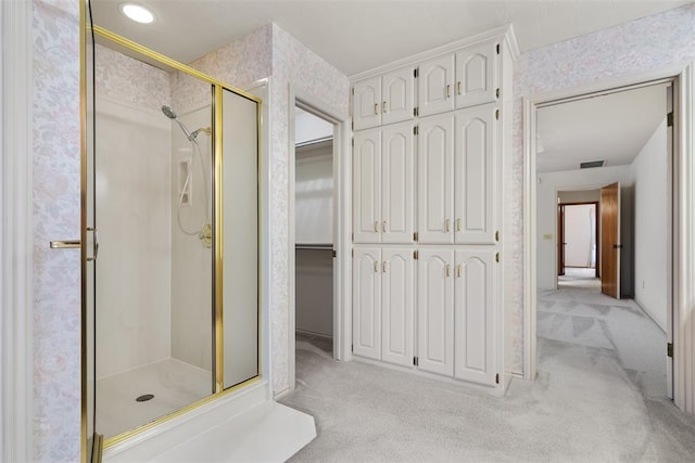 bathroom with wallpapered walls, a shower stall, a spacious closet, and visible vents