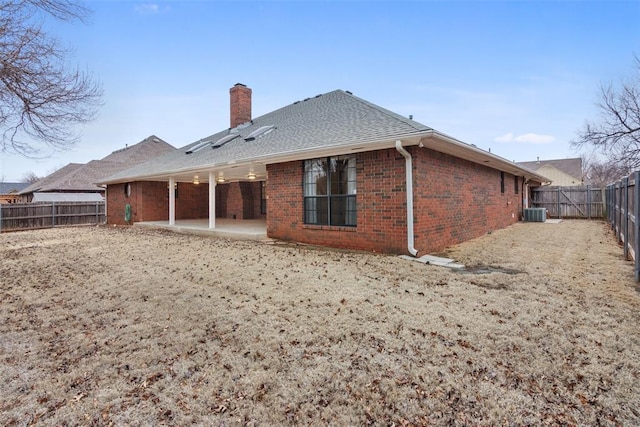 rear view of property featuring brick siding, a patio, a chimney, and a fenced backyard