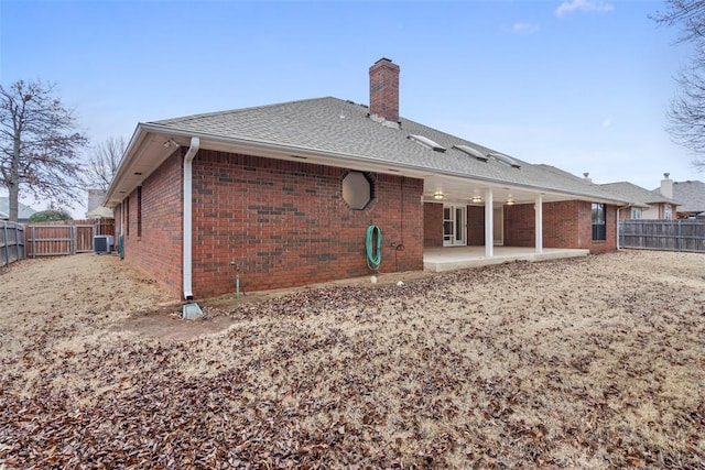 back of property with a fenced backyard, central AC, a patio, and brick siding