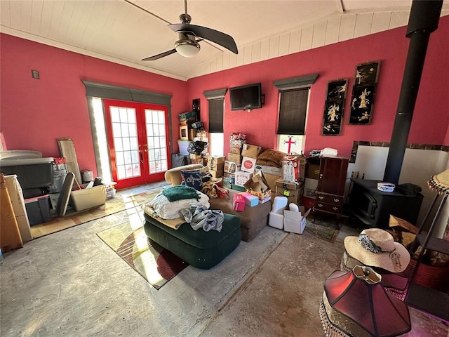 interior space with lofted ceiling, a ceiling fan, french doors, a wood stove, and unfinished concrete floors