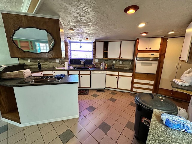 kitchen featuring dark countertops, decorative backsplash, white cabinets, a textured ceiling, and white appliances