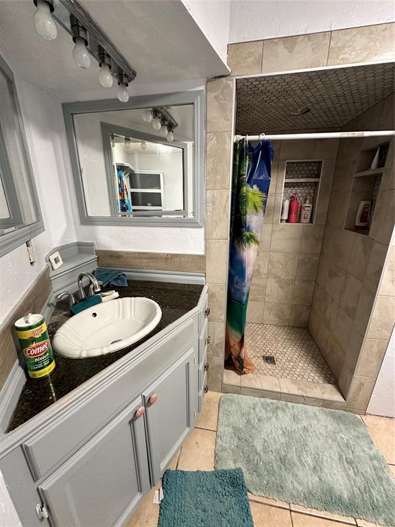 full bathroom with a stall shower, vanity, and tile patterned floors