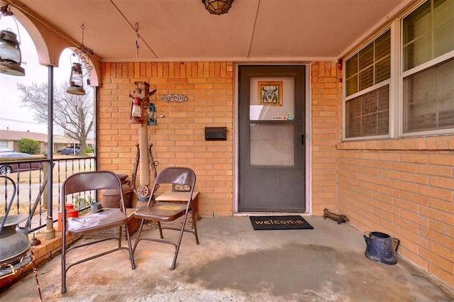 entrance to property featuring a porch and brick siding