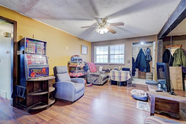 living area with a ceiling fan and wood finished floors