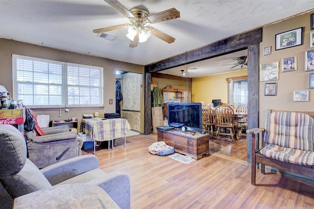 living area with ceiling fan, wood finished floors, and visible vents