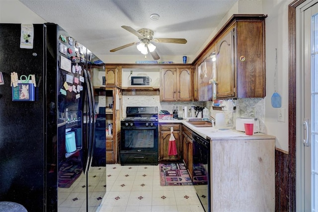 kitchen with light countertops, decorative backsplash, brown cabinetry, a ceiling fan, and black appliances