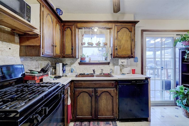 kitchen featuring black dishwasher, light countertops, gas stove, a sink, and plenty of natural light