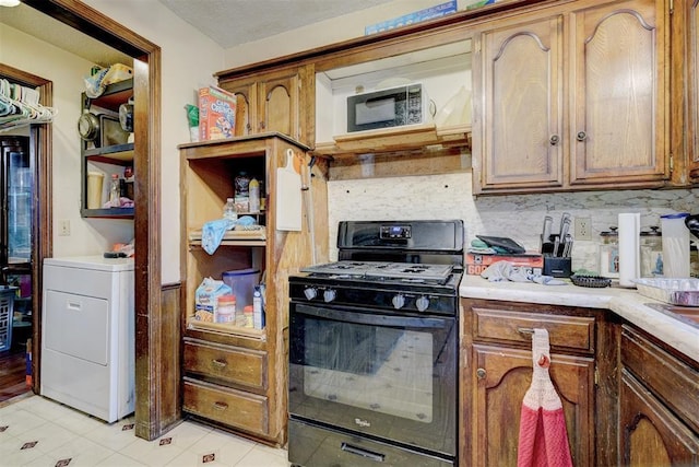 kitchen featuring light countertops, backsplash, brown cabinets, gas stove, and washer / dryer