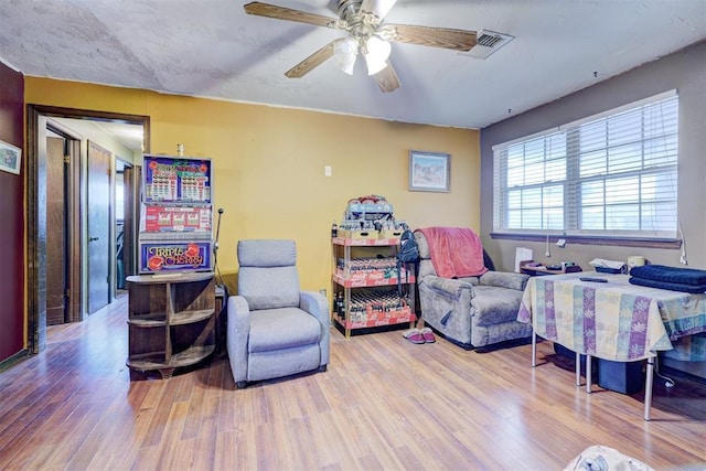 sitting room with ceiling fan, visible vents, and wood finished floors