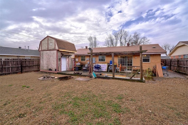 back of house featuring an outbuilding, a fenced backyard, a patio, and a storage unit