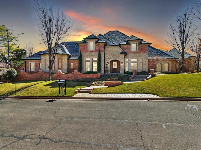 french provincial home with stone siding and a lawn