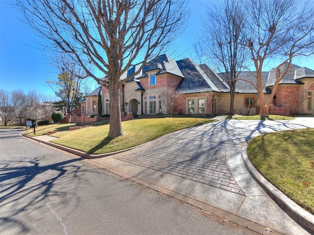 view of front of property featuring driveway, brick siding, a front lawn, and a residential view