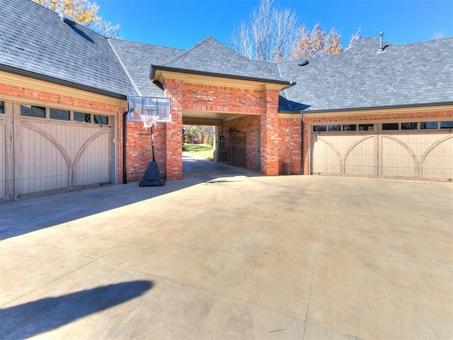 exterior space featuring driveway, brick siding, roof with shingles, and an attached garage