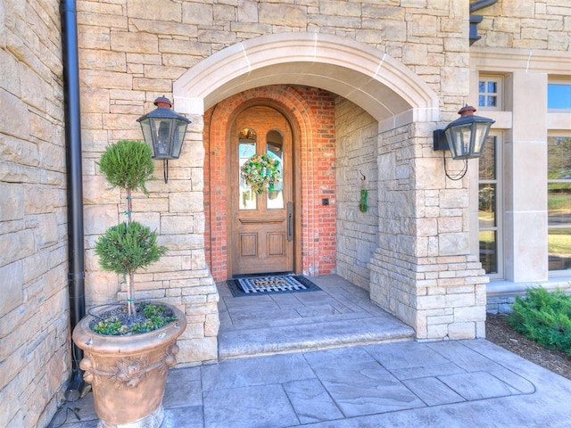 view of exterior entry featuring stone siding and brick siding