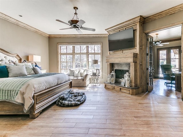 bedroom featuring crown molding, light wood-style flooring, and a premium fireplace